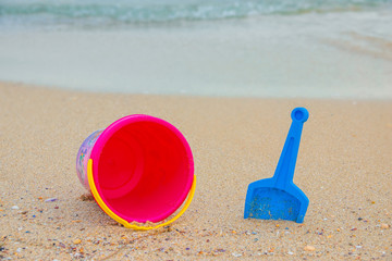 Beach toys on sand. Bright bucket, shovel on the sand