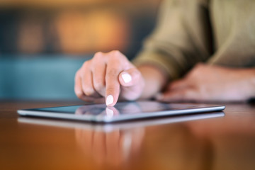 Closeup image of a woman pointing finger at tablet pc on wooden table