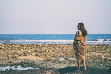 A beautiful asian woman walking on the beach by the seashore