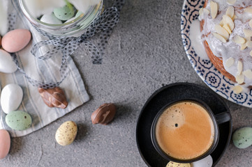 Fragrant cup of coffee and Easter orthodox sweet bread, kulich and colorful quail eggs with willow branches. Holidays breakfast concept with copy space. Set for the holiday and a bouquet of  tulips.