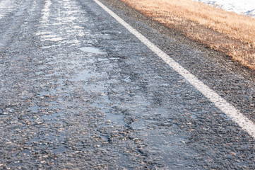 view of street pavement wet after rain with water puddles