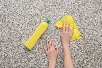 Fototapeta na wymiar Female hands with rag and detergent on carpet