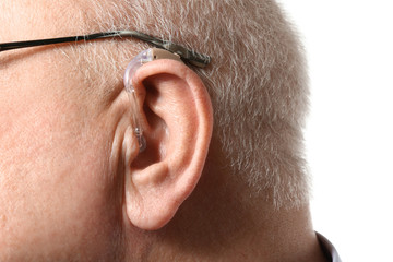 Senior man with hearing aid on white background, closeup