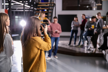 Woman taking photo of young coworkers during coffee break in cafe