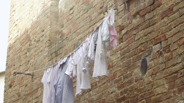 Washed things are drying on lines stretched along the wall.