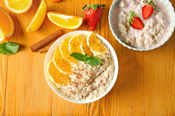 Bowls with tasty sweet oatmeal on wooden table