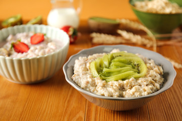 Bowl with tasty sweet oatmeal on wooden table