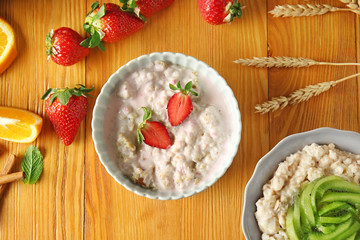 Bowls with tasty sweet oatmeal on wooden table