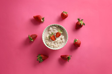 Bowl with tasty sweet oatmeal and strawberry on color background