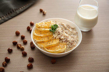 Bowl with tasty sweet oatmeal on wooden table