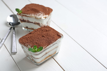 Tasty tiramisu on white wooden table