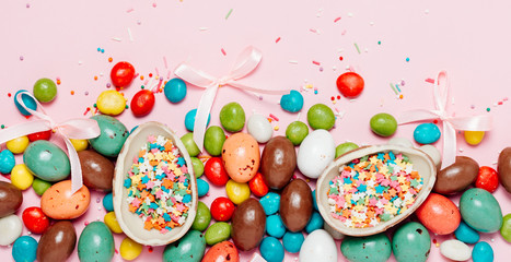 Fototapeta na wymiar Easter frame made from colorful eggs and big chocolate egg flat lay on white background. Top view, copyspace for text.
