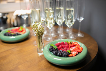 snack berries and glasses of champagne on a wooden table. wedding snack, sweet berry table.