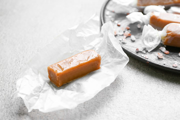 Tasty salty caramel candy on grey table