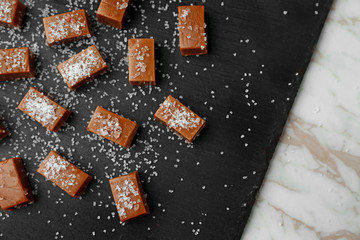 Tasty salted caramel candies on slate plate