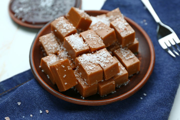 Plate with tasty salty caramel candies on table
