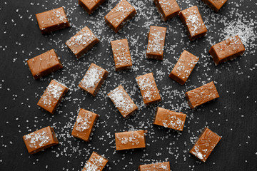 Tasty salted caramel candies on dark background