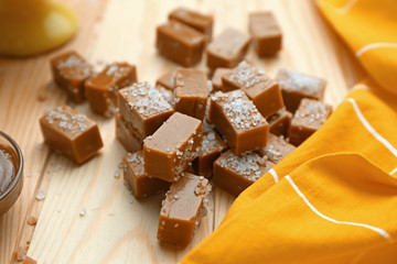 Tasty salted caramel candies on wooden table