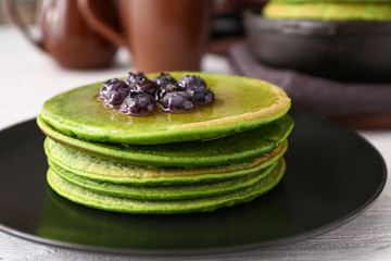 Plate with tasty green pancakes on table