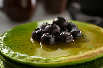 Tasty green pancakes with berries, closeup