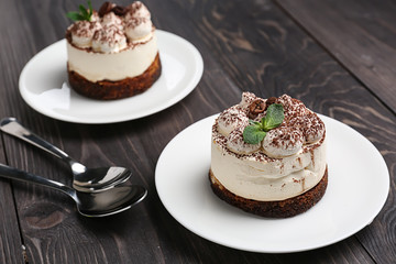 Plates with tasty tiramisu on wooden table