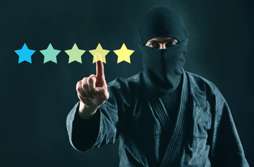 Mystery shopper or review online concept. Rating online. 5 stars review and ninja in mask on a dark...