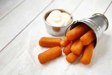 Tasty mozzarella sticks with sauce on white table