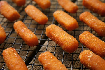 Tasty mozzarella sticks on cooling rack, closeup