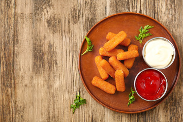 Plate with tasty mozzarella sticks and sauces on wooden table - obrazy, fototapety, plakaty