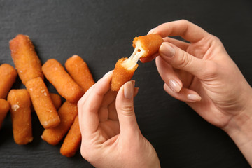 Woman eating tasty mozzarella sticks, closeup