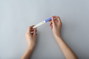 Female hands with pregnancy test on light background