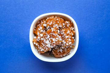 Bowl with tasty salted candies on color background