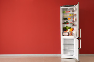Open fridge full of food near color wall