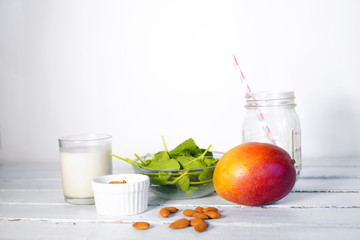 Components of healthy Green Reach Vitamins Smoothie with baby leaf spinach, mango, almond milk and strawberry