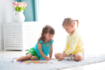 Two little sisters play together at home.