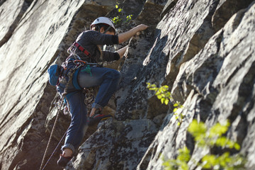 Girl rock climber climbs up the rocks closeup.