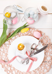 Easter table setting with pink and blue eggs and cutlery on white. Holidays background. Backdrop with copy space