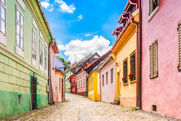 Fototapeta na wymiar Old medieval cobblestone stree with colorful houses in Sighisoara, Transylvania, Romania