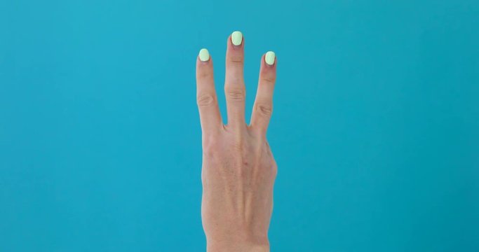 Closeup of isolated on blue adult female hand counting from 0 to 5. Woman shows fist fist, then one, two, three, four, five fingers. Manicured nails painted with beautiful polish. Math concept.