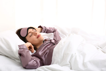 Young woman with sleep mask in bed