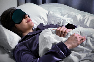 Fototapeta premium Young woman with sleep mask in bed at night