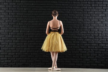 Beautiful young ballerina against dark wall