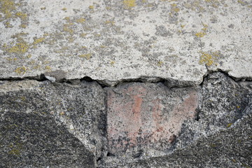 Fragment of an old brick plastered masonry with traces of destruction. Moss covered. Close-up. Selective focus. Copy space. 