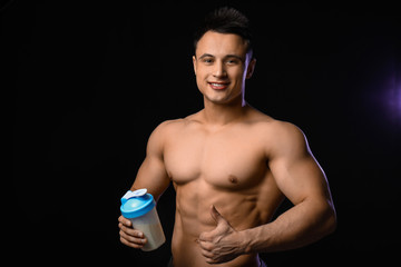 Sporty man with protein shake on dark background