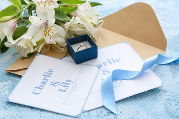 Wedding invitations, ring and flowers on table