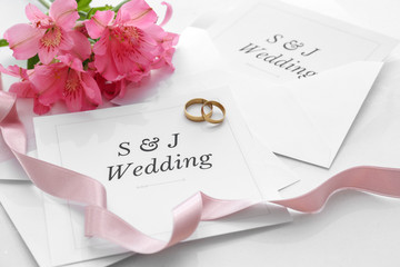 Wedding invitations, rings and flowers on table