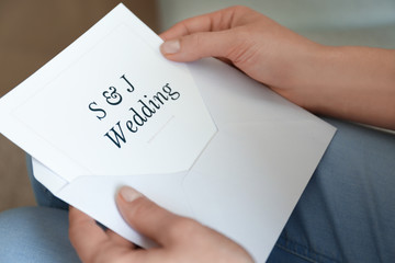 Woman holding envelope with wedding invitation, closeup