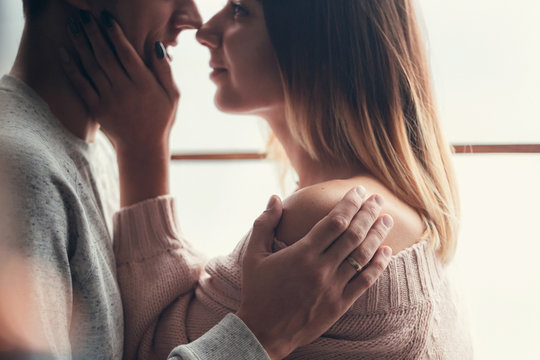 young loving couple stand near the window, kiss and hug, newlyweds