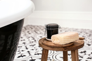 Jar of cream with wisp of bast on wooden stool in bathroom