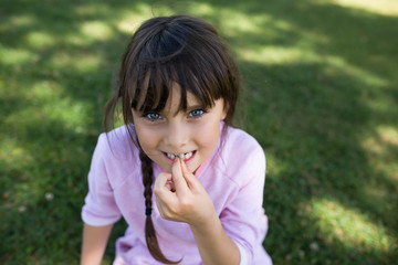 Girl with blue eyes sitting on grass.